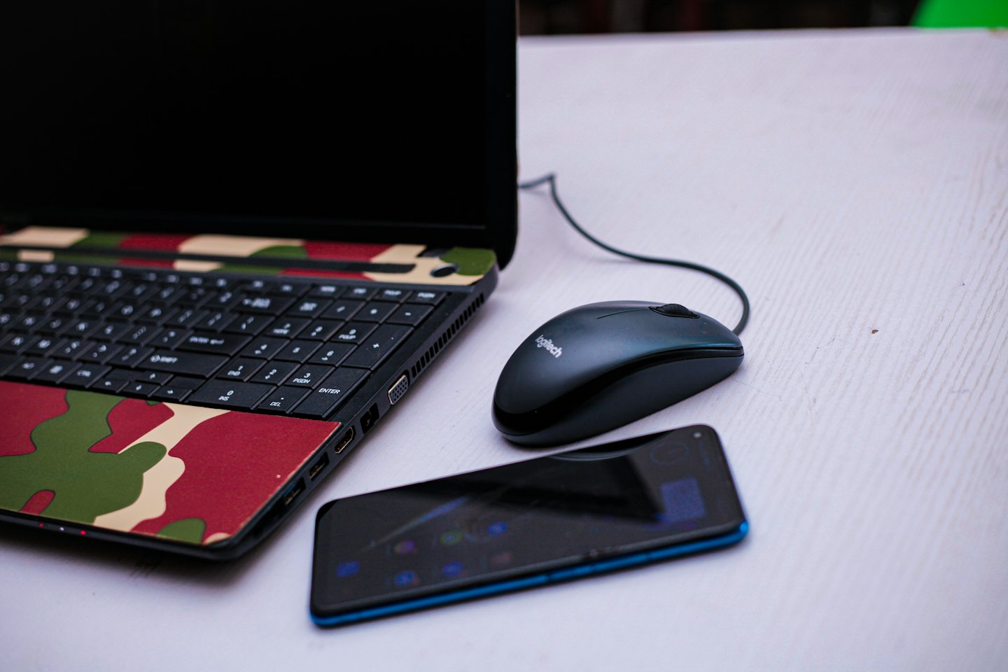 Laptop, mouse, and smartphone on a white desk.